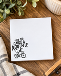 4x4 white notepad featuring a black dachshund riding a bicycle with the phrase “Off to Cause a Kerfuffle.”
