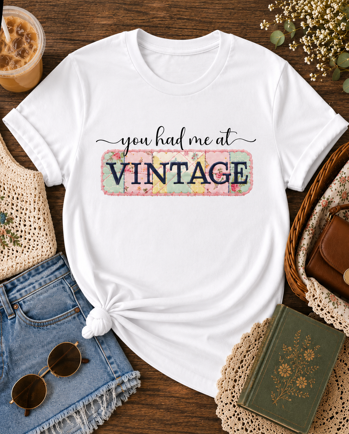 WhiteShirt with “You Had Me at Vintage” graphic tee styled in a cozy flat lay with iced coffee, denim shorts, sunglasses, crochet accessories, and vintage-inspired thrifted finds.