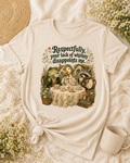A cream-colored graphic t-shirt featuring a whimsical tea-time scene with animals and the text 'Respectfully, your lack of whimsy disappoints me.' The shirt is styled in a flat-lay arrangement with a knotted hem, surrounded by daisies, a woven straw hat, and a ceramic mug.